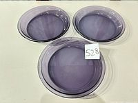 Three smoky purple Pyrex pie plates arranged on table