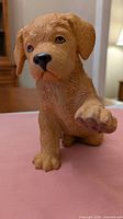 Front view of Labrador puppy figurine with raised paw