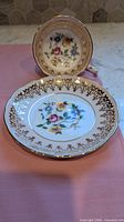 Teacup and two saucers showing floral centres and gold filigree trim