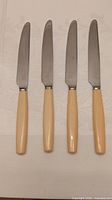 Four Cutlass Leppington knives aligned on cloth