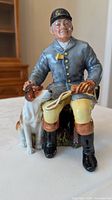 Front view of Royal Doulton figurine showing huntsman, hound and vivid colors