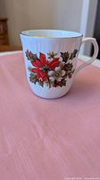 Front view of mug showing poinsettia floral design and gold rim