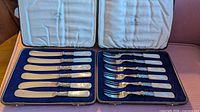 Open cases showing six knives and six forks seated in blue velvet