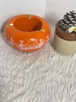 top view showing orange ashtray with gold rests and white scene