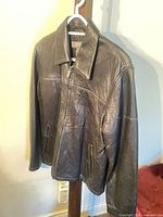 Full view of front of black leather jacket on hanger