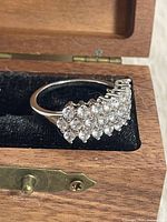 Ring in box showing triple-row cluster of clear stones