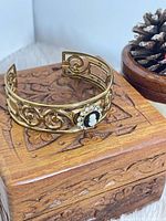 Full view of brass cuff bracelet on carved wooden box