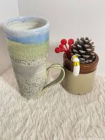 Full view of tall multicolour ceramic mug beside staging prop for scale
