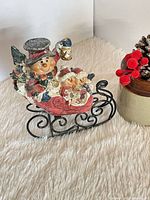 Front view of ceramic snowman sleigh figurine on metal runners