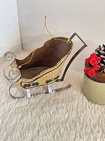 Front side view showing painted tin sleigh body, scroll runners, hanging string