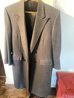 Full view of grey Scabal overcoat on hanger