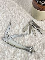 Fish-shaped multi-tool open, blades extended; separate folded manicure tool visible