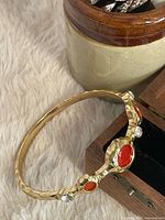 Full view of hammered gold-tone bangle with stones
