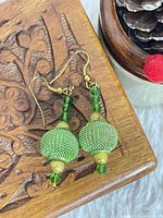 Full view of both earrings on carved wood surface