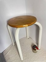 Full view of stool showing wood seat and white metal legs