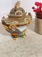 Front view of tripod incense burner showing samurai figure and relief decoration