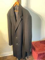 Full view of black 3/4 length coat on hanger showing front and buttons