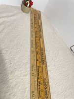 Three pine meter sticks laid out showing full length and advertising text