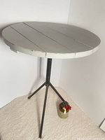 Full view of round pine top side table with steel tripod base