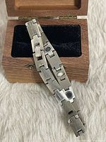 Bracelet draped over wood box showing links, magnets, clasp and box details