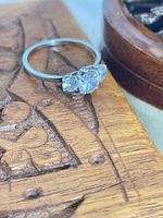Ring on wood surface showing three clear stones and silver band