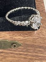 Side view of ring showing twisted band, accent stones, oval gemstone