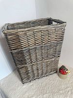 Front view of rectangular wicker basket showing weave pattern and small accessory for scale