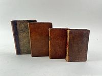 Four leather bound books standing side by side showing front boards