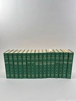 Front view of all 16 green cloth volumes standing in order