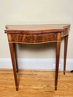 Front view of closed serpentine-front card table showing inlay and tapered legs