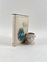Book with dust jacket and porcelain portrait cup front view