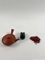 Miniature teapot, carved figurine, red bead necklace grouped