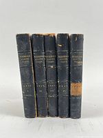 Spine view of all five volumes showing titles, volume numbers and wear