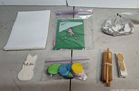 All items laid out: paper stack, bunny cutout, felt circles bag, cardstock bag, foam discs bag, wooden sticks, wooden spoons
