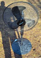 Full view of Utilitech black pedestal fan outdoors