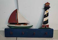 Front view of entire coat rack showing sailboat, lighthouse and four pegs