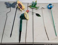 All six decorative garden stakes laid out on table