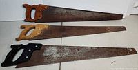 Three hand saws laid out on table