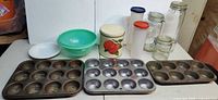 Overall lot showing bake pans, colander, canister, plastic containers and glass jars