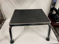 Three-quarter view of stool showing chrome legs, rubber tread surface, rubber caps