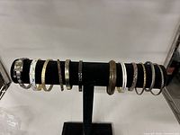 All twelve bracelets displayed on black T-bar stand