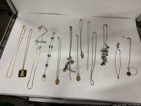 Full view of all 14 necklaces laid out on white background