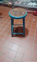 Front angled view of blue steel stool with wooden seat