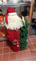 Front view of fabric Santa holding artificial tree