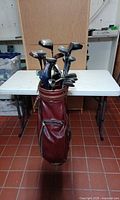 Full view of burgundy golf bag loaded with clubs