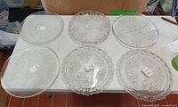 Group shot of six clear glass platters on table