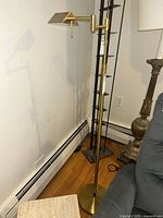 Full view of brass-tone adjustable floor lamp beside chair