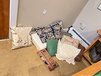 Group of assorted pillows and seat cushion on floor