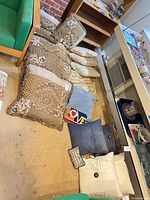 Group of assorted pillows on carpeted floor showing variety of colors and fabrics