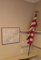 Overall view of framed chart on wall with folded flag on pole beside it